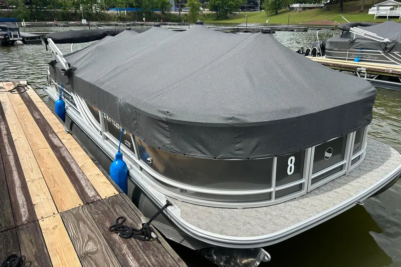 Slide: The Image of 2025 Southbay 224RSLE25 pontoon boat docked with protective cover on a lake. - 27
