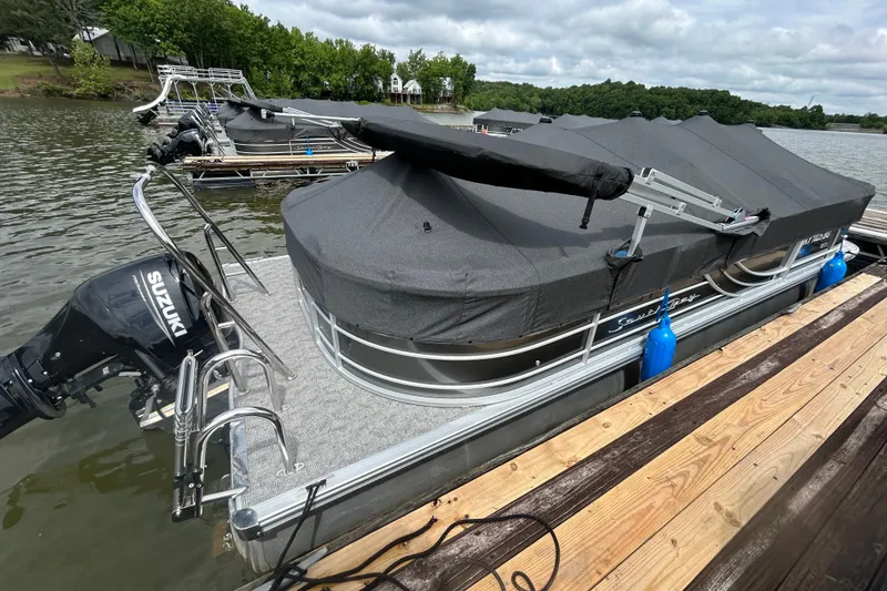 Slide: The Image of 2025 Southbay 224RSLE25 pontoon boat docked with cover and Suzuki outboard motor. - 28