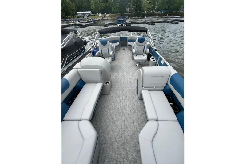 Slide: The Image of 2025 Southbay 224RSLE25 pontoon boat interior with plush seating on a serene lake. - 8