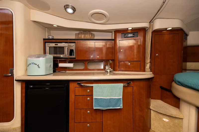 Slide: The Image of 2007 Sea Ray 340 Sundancer interior with kitchenette, featuring wood cabinetry and modern appliances. - 32