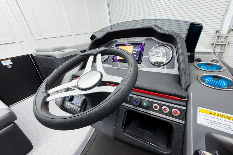 Slide: The Image of 2026 Godfrey Monaco 25' Tritoon dashboard with steering wheel and digital display. - 23