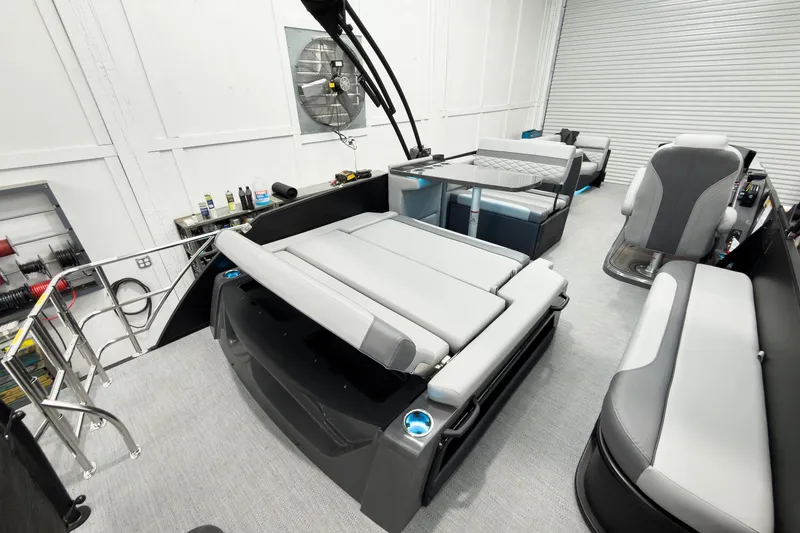 Slide: The Image of 2026 Godfrey Monaco 25' Tritoon with mid-table flip lounge in a showroom setting. - 44