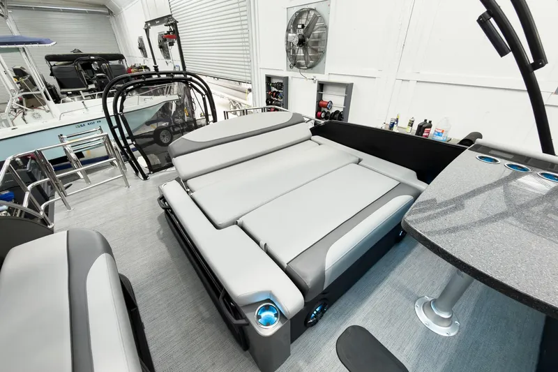 Slide: The Image of 2026 Godfrey Monaco 25' Tritoon with mid-table flip lounge in a showroom setting. - 45