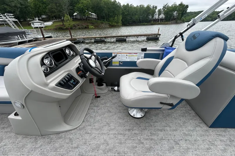 Slide: The Image of 2025 Southbay 224RSLE275 boat interior with captain's chair and control panel by a lake. - 10