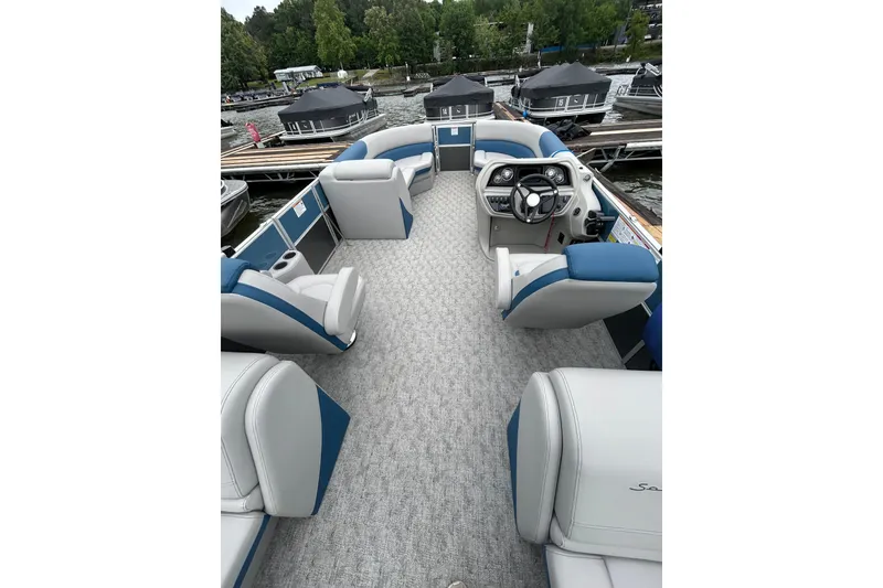 Slide: The Image of 2025 Southbay 224RSLE275 pontoon boat interior with plush seating and modern steering console. - 14