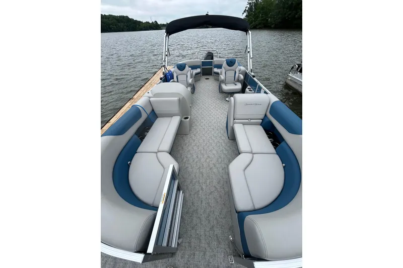 Slide: The Image of 2025 Southbay 224RSLE275 pontoon boat with spacious seating on a serene lake. - 3