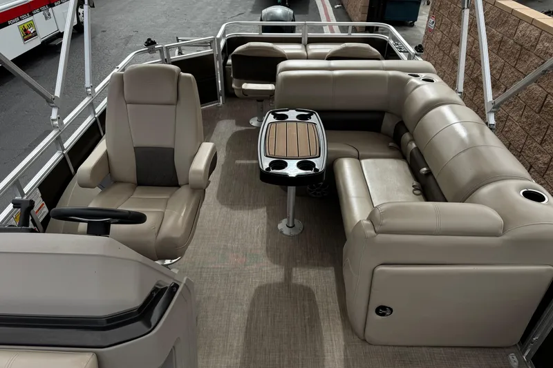 Slide: The Image of 2024 Sun Tracker SportFish 22 DLX pontoon boat interior with beige seating and table. - 17