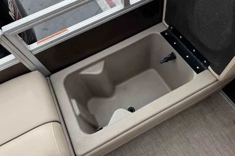 Slide: The Image of 2024 Sun Tracker SportFish 22 DLX boat storage compartment with beige seating and drain plug. - 21