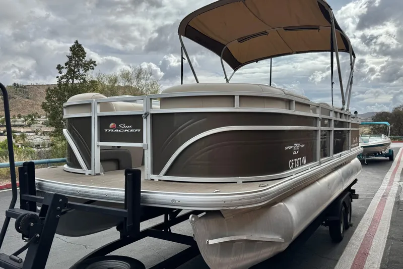 Slide: The Image of 2024 Sun Tracker SportFish 22 DLX pontoon boat on trailer, under cloudy sky. - 3