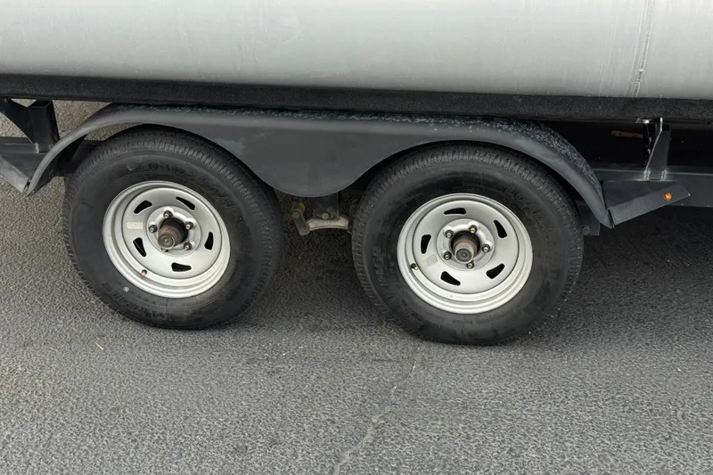 Slide: The Image of Trailer wheels of a 2024 Sun Tracker SportFish 22 DLX on asphalt surface. - 33