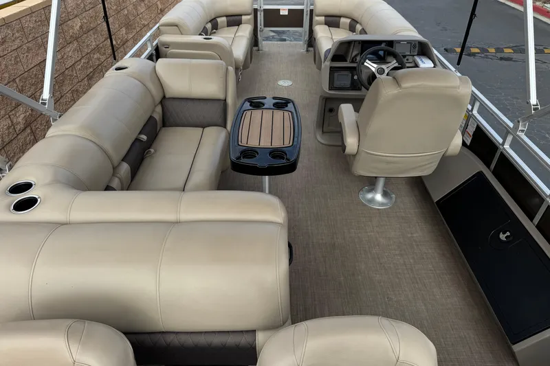 Slide: The Image of 2024 Sun Tracker SportFish 22 DLX pontoon boat interior with beige seating and steering console. - 9