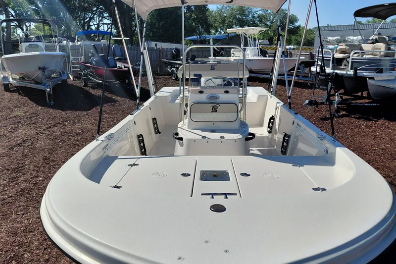 Slide: The Image of 2022 Carolina Skiff 178 JLS boat with seating and console, displayed outdoors. - 11
