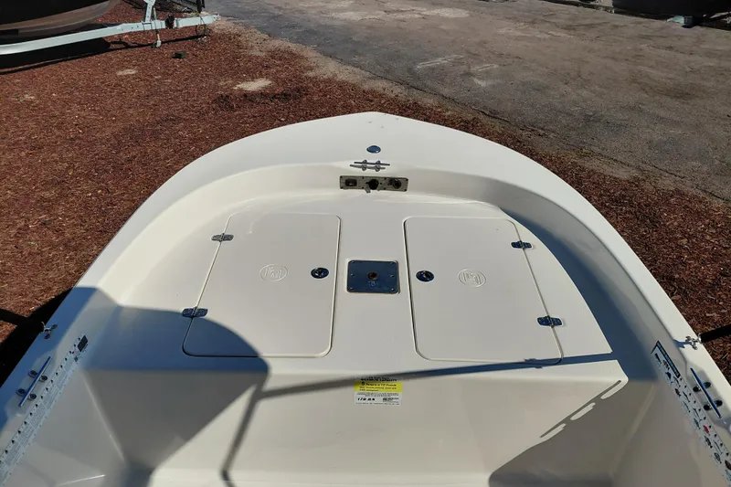 Slide: The Image of 2022 Carolina Skiff 178 JLS boat deck with storage compartments, parked on a gravel surface. - 16