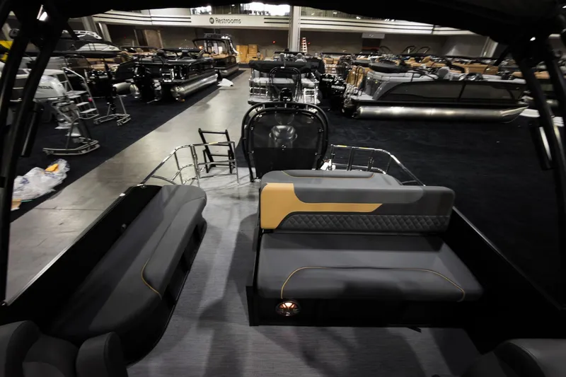 Slide: The Image of 2026 Godfrey Sweetwater 22' Tritoon interior at a boat show, featuring modern seating. - 17