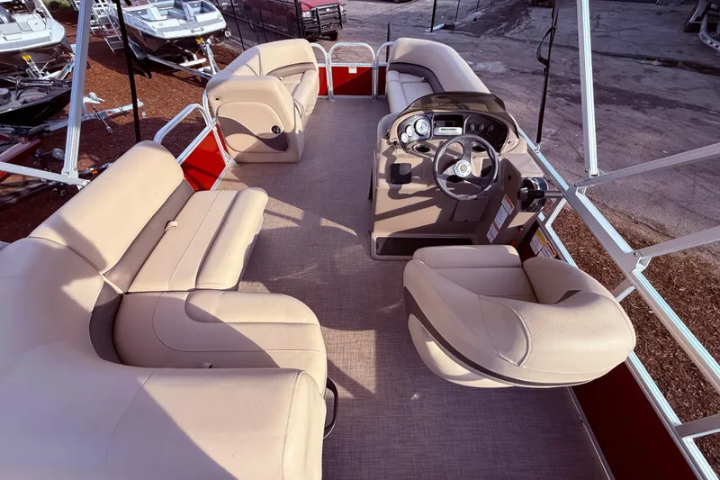 Slide: The Image of 2023 Sun Tracker Party Barge 18 DLX interior with beige seating and steering console. - 8