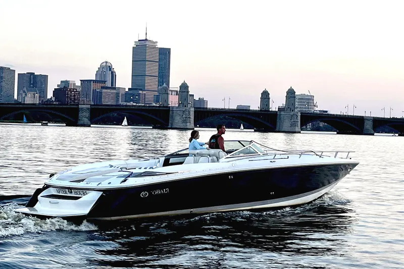 Slide: The Image of 2005 Cobalt 343 boat cruising on a river with city skyline backdrop. - 0