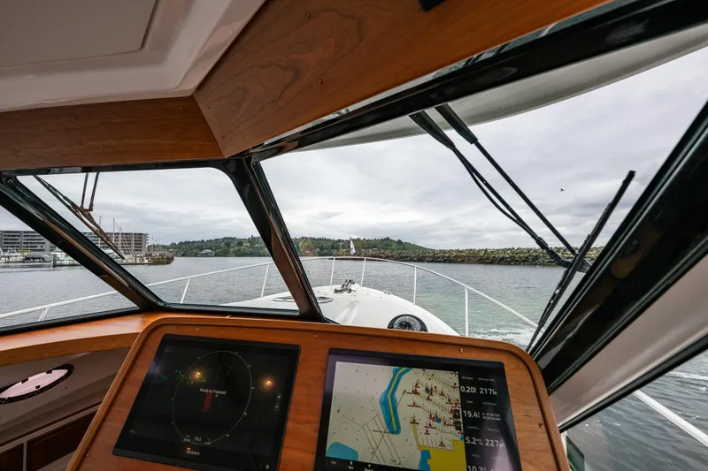 Slide: The Image of Pilothouse view from 2025 Back Cove 39O boat, featuring navigation screens and scenic waterway. - 31