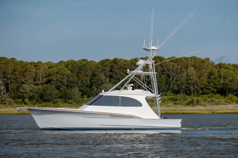 Slide: The Image of 2015 Jarrett Bay Hardtop Express Sportfish cruising on calm waters near a forested shoreline. - 12