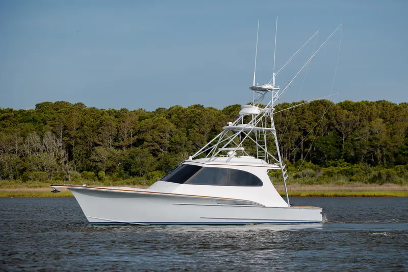 Slide: The Image of 2015 Jarrett Bay Hardtop Express Sportfish cruising on calm water near a forested shoreline. - 13