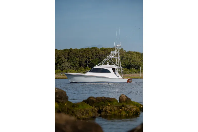 Slide: The Image of 2015 Jarrett Bay Hardtop Express Sportfish on calm water, surrounded by lush greenery. - 14