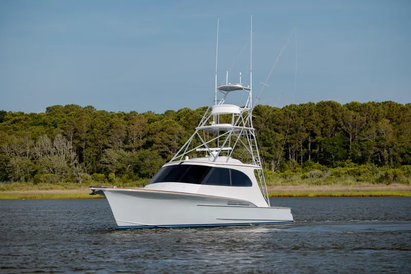 Slide: The Image of 2015 Jarrett Bay Hardtop Express Sportfish cruising on calm waters near a forested shoreline. - 2