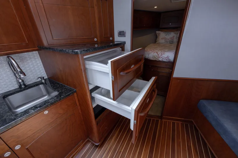 Slide: The Image of 2015 Jarrett Bay Hardtop Express Sportfish interior with wood cabinetry and open drawers. - 50