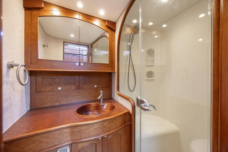 Slide: The Image of Luxurious 2015 Jarrett Bay Hardtop Express Sportfish bathroom with wooden cabinetry and glass shower. - 54