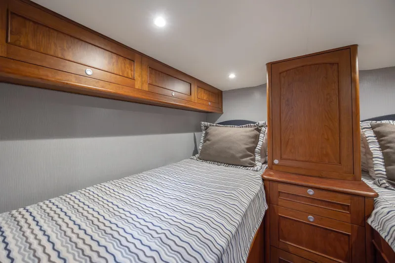 Slide: The Image of 2015 Jarrett Bay Hardtop Express Sportfish cabin with wooden cabinetry and cozy bedding. - 60
