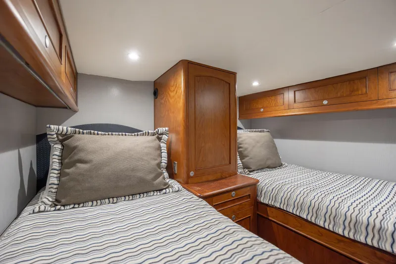 Slide: The Image of 2015 Jarrett Bay Hardtop Express Sportfish cabin with twin beds and wooden cabinetry. - 62