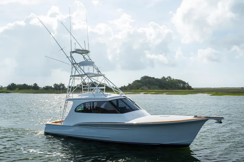 Slide: The Image of 2015 Jarrett Bay Hardtop Express Sportfish on calm water, showcasing sleek design and fishing tower. - 75
