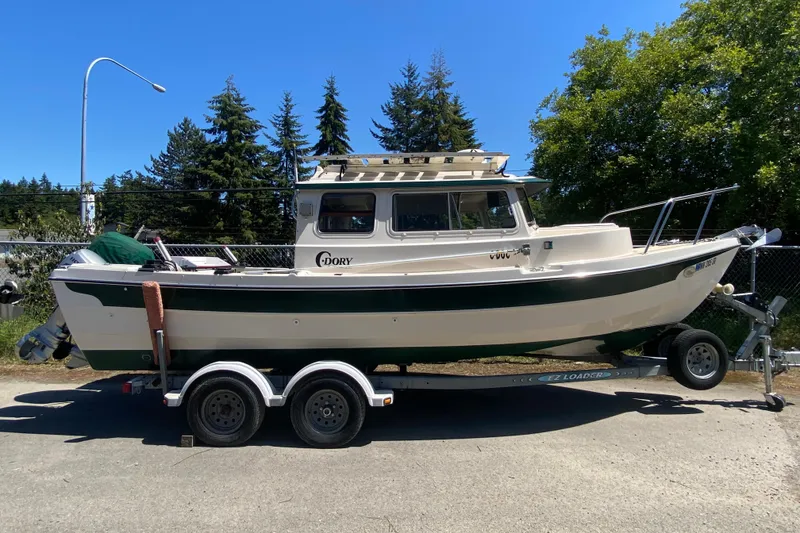 The Image of 1999 C-Dory 22' Angler boat on trailer, parked outdoors near blue building. - 0