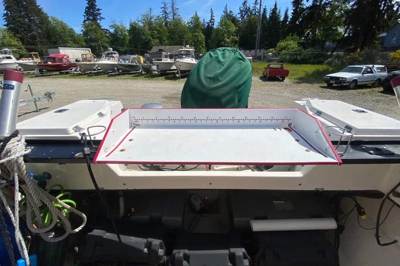 Slide: The Image of 1999 C-Dory 22' Angler boat docked near blue building, surrounded by trees. - 11