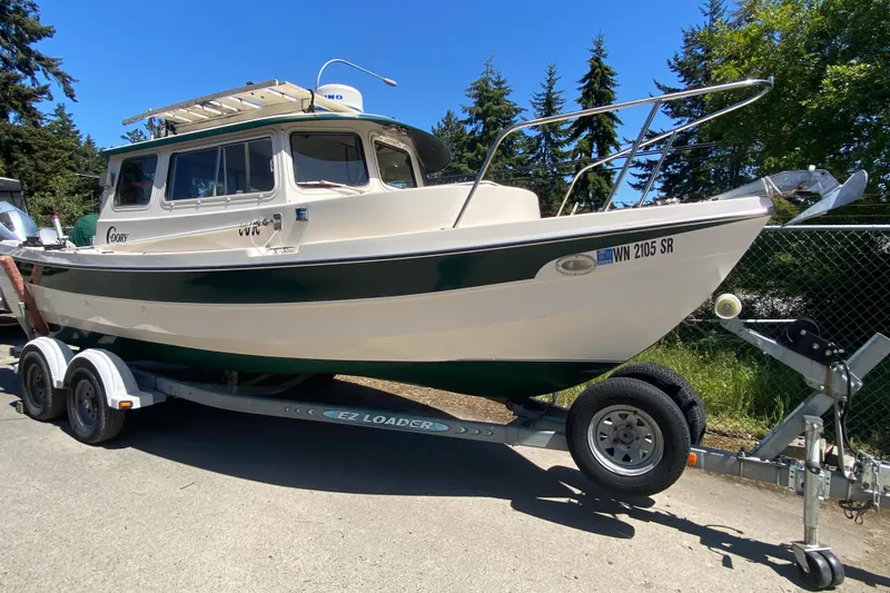 Slide: The Image of Interior of a 1999 C-Dory 22' Angler boat with green seating and a table. - 2