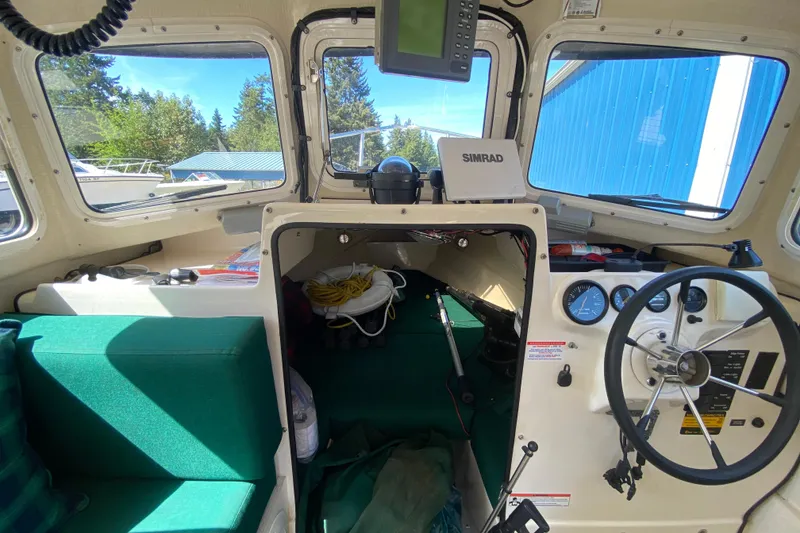 Slide: The Image of Interior of a 1999 C-Dory 22' Angler boat with seating, table, and kitchenette. - 7