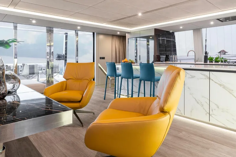Slide: The Image of Luxurious Sunreef 80 Sail 2022 yacht interior with modern design, featuring yellow chairs and marble accents. - 9