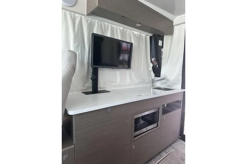 Slide: The Image of Interior of 2024 Jeanneau NC Weekender 1095 Fly, featuring modern kitchenette with TV and microwave. - 9
