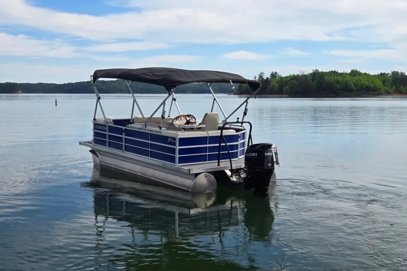 Slide: The Image of 2022 Lexington 320 pontoon boat on calm lake with scenic background. - 10