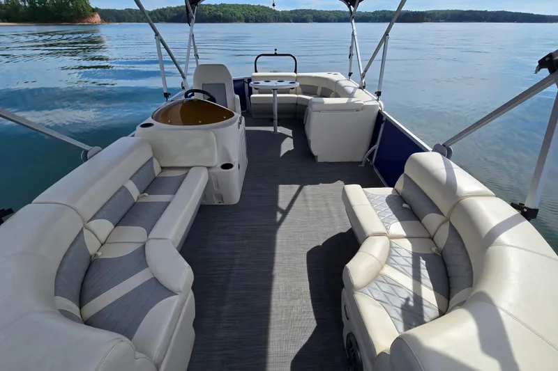 Slide: The Image of Luxurious 2022 Lexington 320 pontoon boat interior with plush seating on a serene lake. - 12