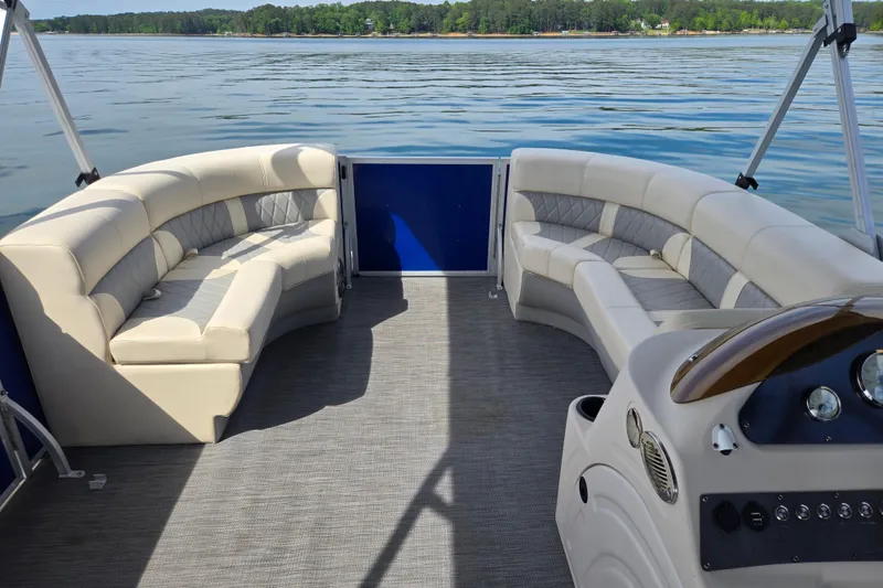 Slide: The Image of 2022 Lexington 320 pontoon boat interior with plush seating on a serene lake. - 13