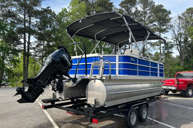 Slide: The Image of 2022 Lexington 320 pontoon boat with Suzuki outboard motor on trailer in wooded area. - 3