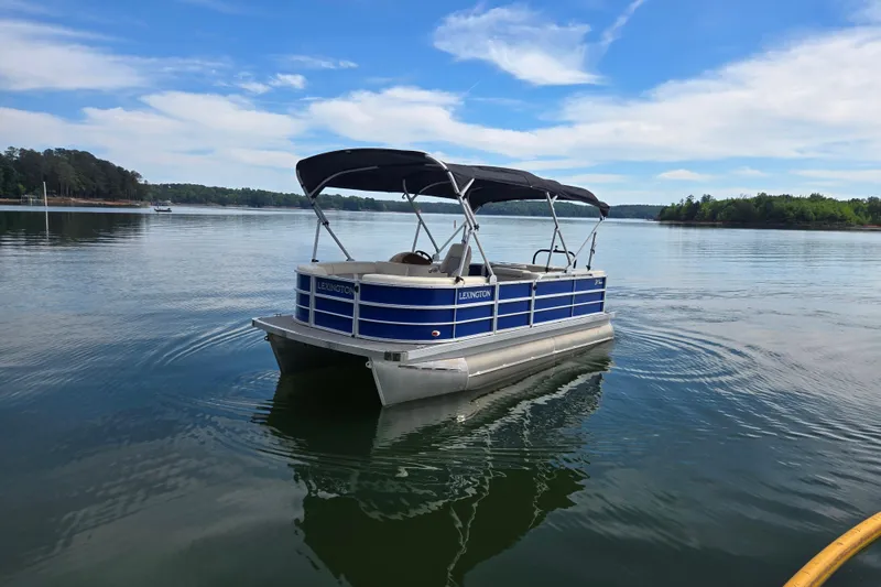 Slide: The Image of 2022 Lexington 320 pontoon boat on a serene lake under a clear blue sky. - 4
