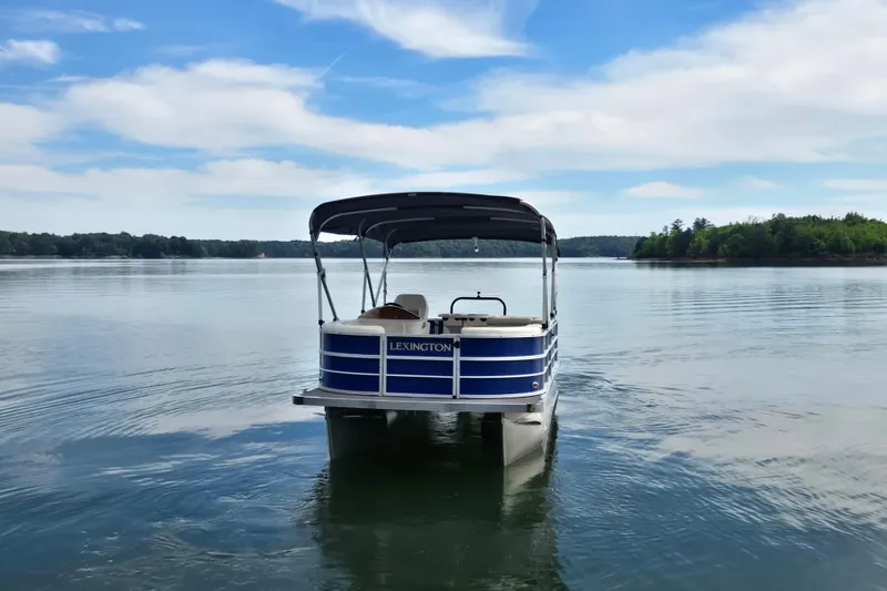 Slide: The Image of 2022 Lexington 320 pontoon boat on a serene lake under a blue sky. - 5