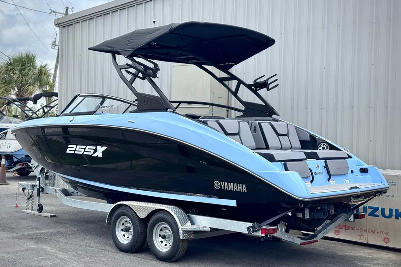 The Image of 2025 Yamaha Boats 255XD in blue and black on a trailer, parked outdoors. - 0
