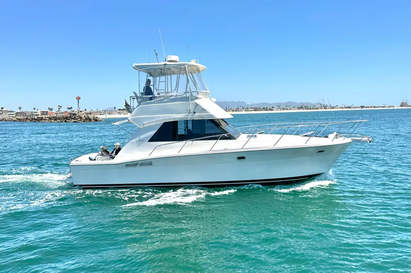 The Image of 1999 Riviera 3600 Sport Yacht cruising on clear blue waters under a sunny sky. - 0