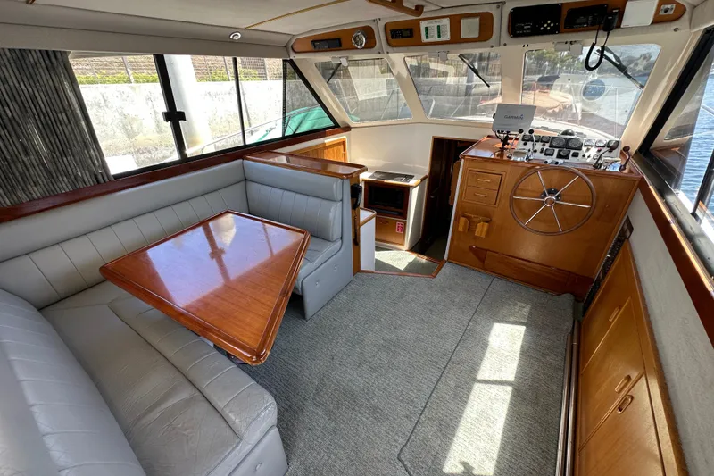 Slide: The Image of Interior of 1999 Riviera 3600 Sport Yacht with helm, seating, and wooden table. - 11