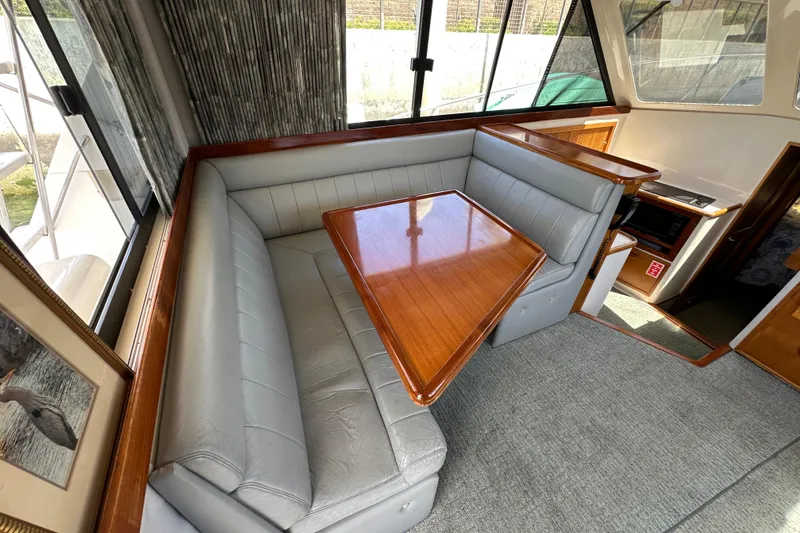 Slide: The Image of Interior of 1999 Riviera 3600 Sport Yacht with plush seating and wooden table. - 12
