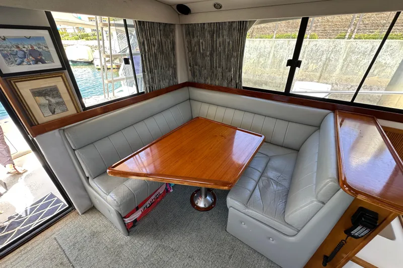 Slide: The Image of 1999 Riviera 3600 Sport Yacht interior with cozy dining area and elegant wood table. - 13