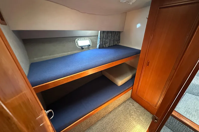 Slide: The Image of 1999 Riviera 3600 Sport Yacht cabin with wooden interior and blue bunk beds. - 17