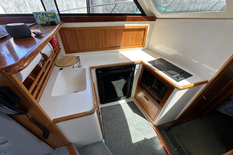 Slide: The Image of Compact kitchen area in a 1999 Riviera 3600 Sport Yacht with stove, sink, and microwave. - 19