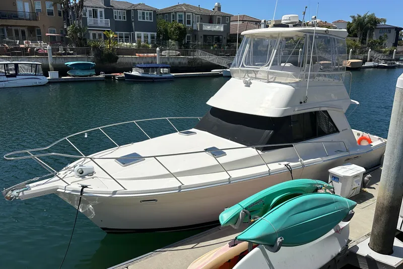 Slide: The Image of 1999 Riviera 3600 Sport Yacht docked in a serene marina setting. - 23